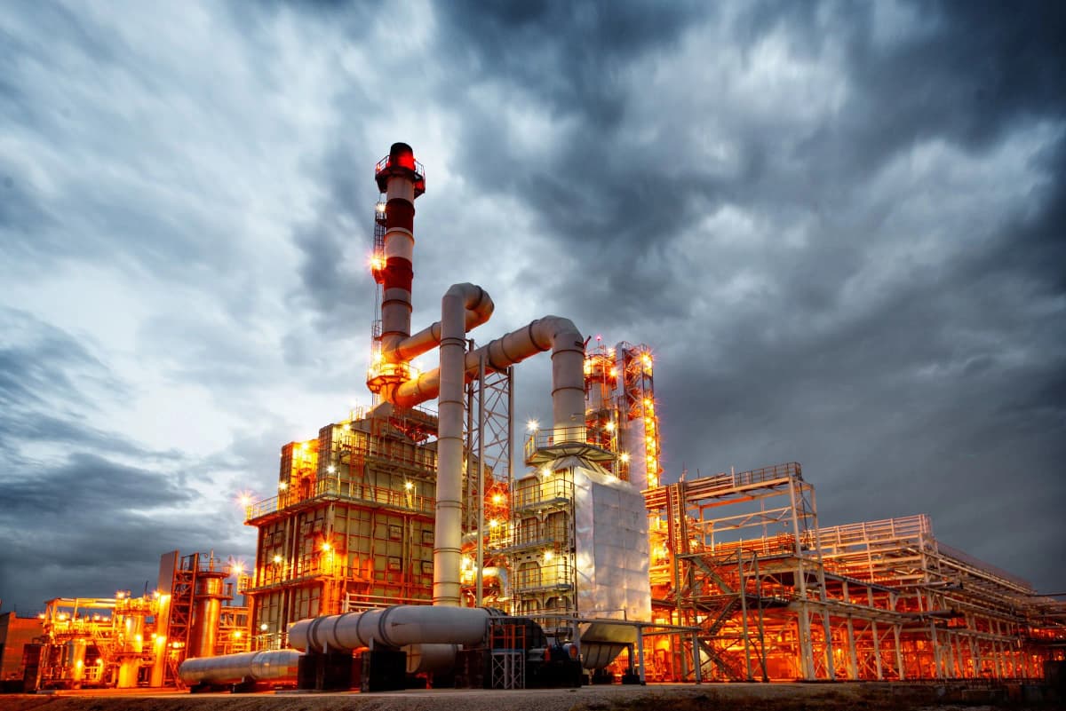 Illuminated power generation facility at night with dramatic sky